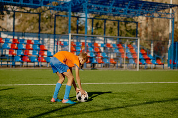 Junior football player placing ball on grass field for free kick or penalty