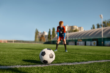 Obraz na płótnie Canvas Boy football player looking at soccer ball before to kick