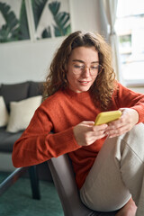 Young pretty woman holding smartphone using cellphone modern technology, looking at mobile,...