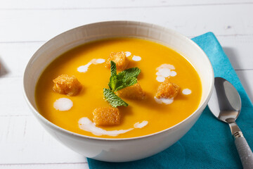 Close-up of pumpkin and carrot cream decorated with croutons and sour cream.