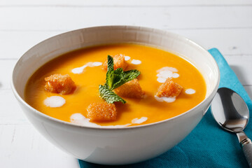 Close-up of pumpkin and carrot cream decorated with croutons and sour cream.
