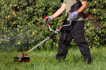 Man mows green grass on the lawn with hand trimmer