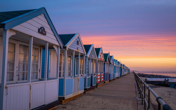 Colourful beach huts on the promonade by the pier in Southwold, Suffolk at sunrise