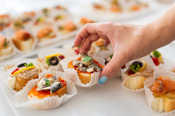 Woman hand picking up canape from table on celebration event.