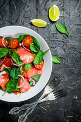 Fish salad. Salad with slices of salmon, tomatoes and spinach with lime juice.
