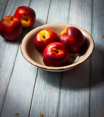 Ripe nectarines in a bowl on a wooden base. Healthy food.