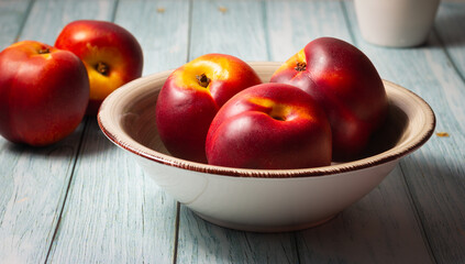 Close-up of fresh nectarines in a bowl on a wooden background.