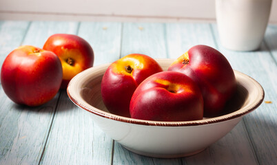 Close-up of fresh nectarines in a bowl on a wooden background.