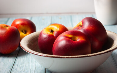 Close-up of fresh nectarines in a bowl on a wooden background.
