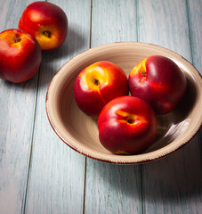 Ripe nectarines in a bowl on a wooden base. Healthy food.