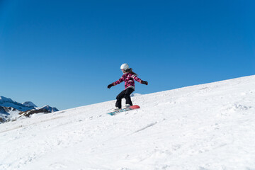 Naklejka na ściany i meble Girl snowboarding in the snow on the mountain on a sunny day