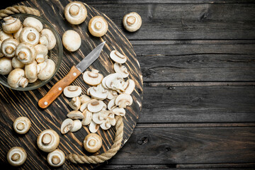Pieces of fresh mushrooms on a tray with a knife.