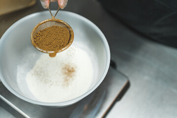 top view of sifting cinnamon into a bowl with flour, preparing for baking. High quality photo