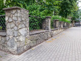 prefab metal fence on concrete foundation pile of stones loose stone construction of houses and yards construction works