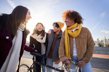 Cheerful Group of guys walking down the street talking and having fun. Multiracial friends standing outdoors spending time together. People in winter clothes. Friendship and youth lifestyle concept
