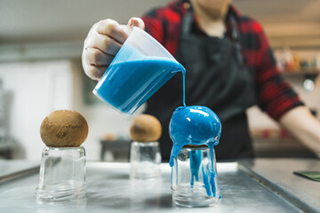 female baker putting blue cream on chocolate balls in the kitchen, baker, tasty dessert. High quality photo