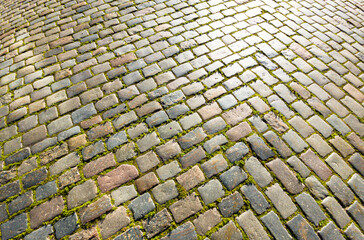 Fototapeta premium Granite dirty paving stones in the city. Road from paving stones for background and texture. The old road of granite paving stones