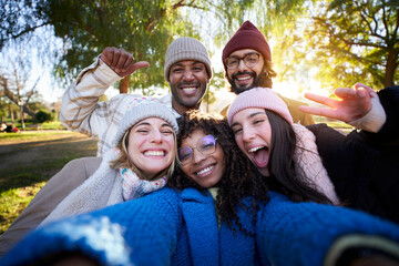 Winter time smiling selfie of a happy group of multicultural friends looking at the camera....