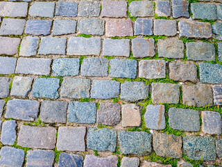 Granite dirty paving stones in the city. Road from paving stones for background and texture. The old road of granite paving stones