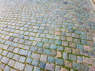 Fototapeta premium Granite dirty paving stones in the city. Road from paving stones for background and texture. The old road of granite paving stones