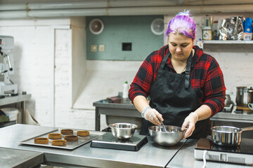 medium shot of a professional female chef with purple hair preparing caramel in a bowl in the kitchen. High quality photo