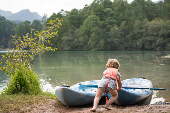Toddler pushing kayak into water in Rancho Santa Elena, Hidalgo, Mexico