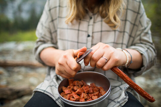 Young woman preps food while camping in the backcountry.
