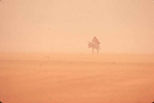 Aman rides a donkey through the desert, Sudan