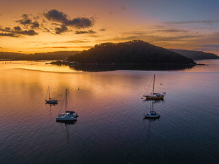 Fototapeta premium Aerial sunrise waterscape with boats and scattered clouds