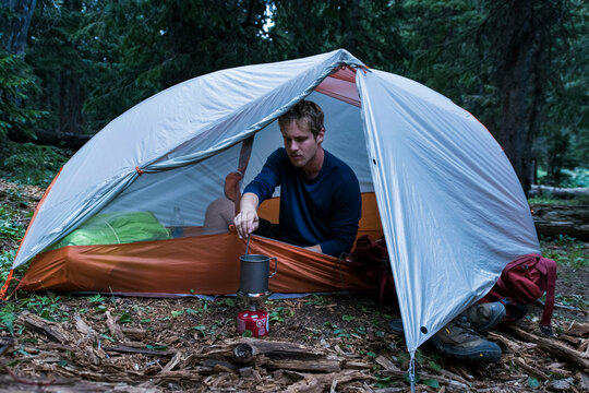 Male hiker preparing food while camping in forest