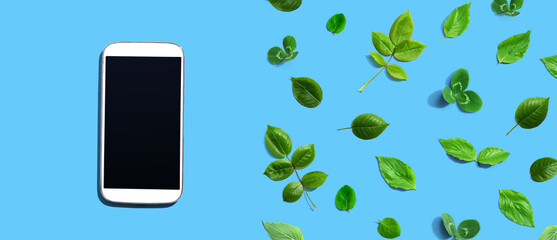 White smartphone with green leaves - flat lay
