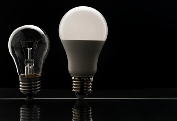 Tungsten bulb and LED bulb on black. The concept of saving electricity.