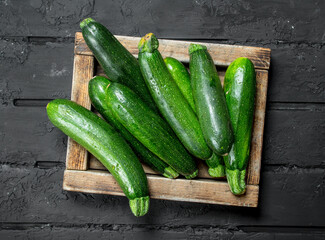 Green zucchini in wooden tray.