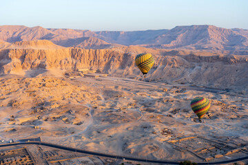 Colorful hot air balloon at sunrise in front of Temple of Hatshepsut near the Valley of the Kings in Luxor, Egypt