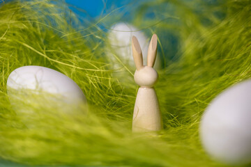 petit lapin en bois et oeufs dans un décor de paille verte pour pâques