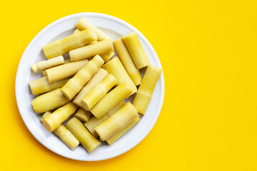 Preserved bamboo shoot in white plate on yellow background.