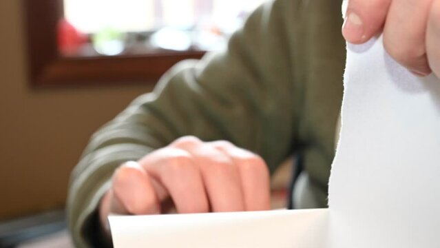 Two Caucasian hands ripping a white sheet of paper in half
