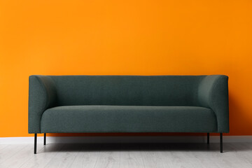 Stylish sofa near orange wall. Interior design