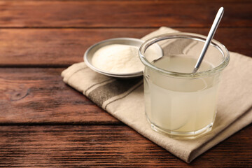 Glass of agar-agar jelly and bowl with powder on wooden table. Space for text