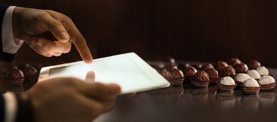 Production line of chocolate candies. Man working with tablet, closeup. Banner design