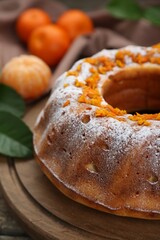 Homemade yogurt cake with tangerines and powdered sugar on wooden table, closeup