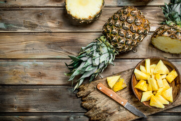 Obraz na płótnie Canvas Sliced pineapple in a bowl on a cutting Board with a knife and a whole pineapple.