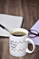 Black coffee in motivational quote mug at office table