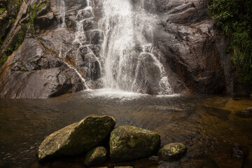 Naklejka premium Pedras da Cachoeira do Veloso - ILHABELA, SP, BRAZIL - DECEMBER 01, 2022: Stones in the well of the beautiful Veloso waterfall in the middle of the lush Atlantic forest.