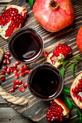 Pomegranate juice in a glass and grains of fresh pomegranate on tray.