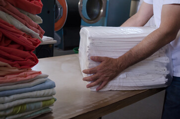 Adult man bagging freshly ironed sheets or fabrics in an industrial laundry.