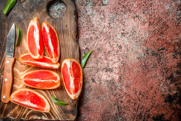 Pieces of grapefruit on a cutting Board with a knife.