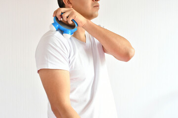 Hombre hispano usando un masajeador pequeño para tratar dolor muscular.