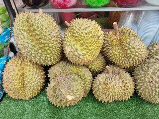 Several durians lined up on a table for sale in a Thai market.