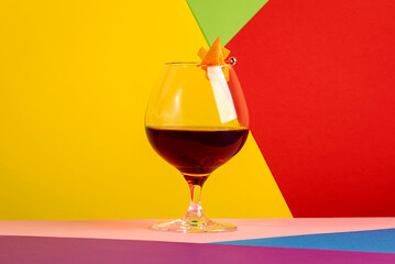 Martinique alcoholic cocktail with golden rum, red vermouth, liqueur, bitter and orange zest. Modern style still life on trendy bright multi-colored background